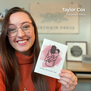 Taylor Cox, the artist behind Coxswain Press, holds up letterpress card that says “Sending Long Distance Hugs” in her studio, with text that says, “Taylor Cox, Coxswain Press” at the top.