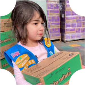 Daisy Girl Scout with brown hair holding a case of Thin Mints