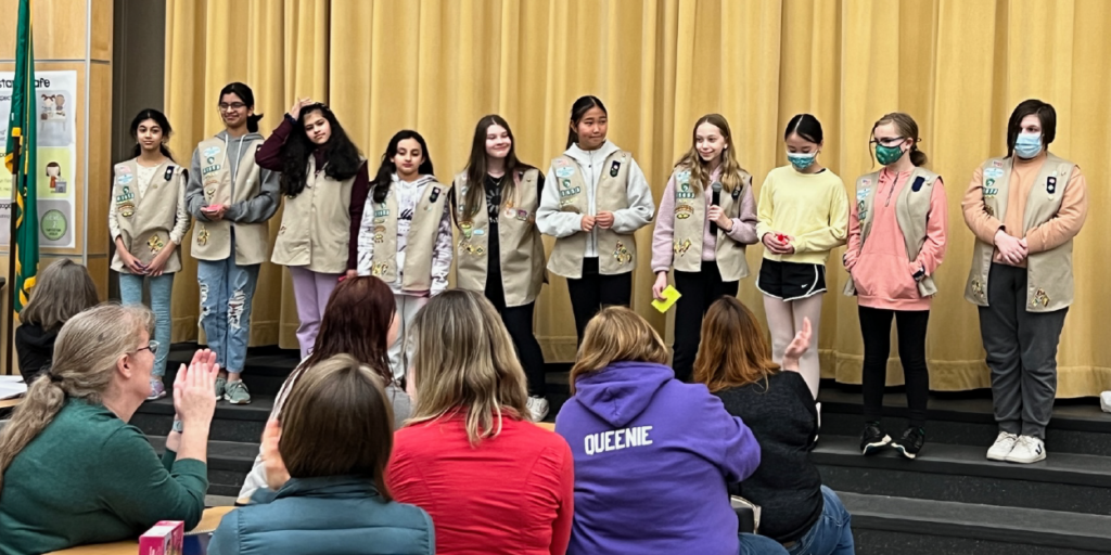 Multiple Girl Scouts in uniform standing on stage
